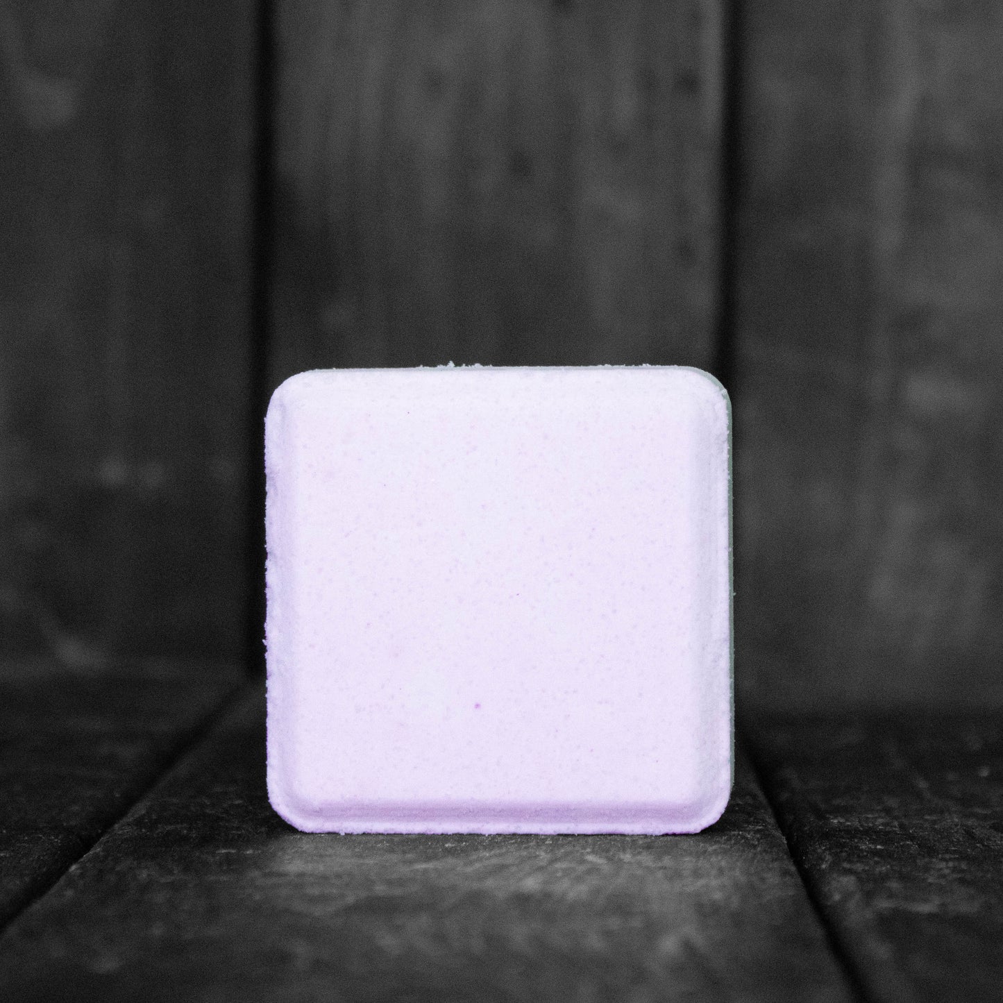 A light purple, square shaped shower steamer.