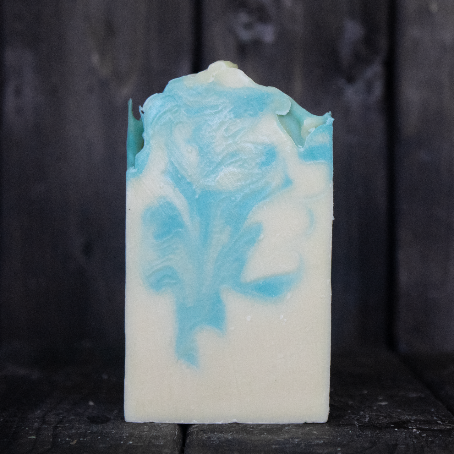 Soap with blue swirls in front of a dark wood background.