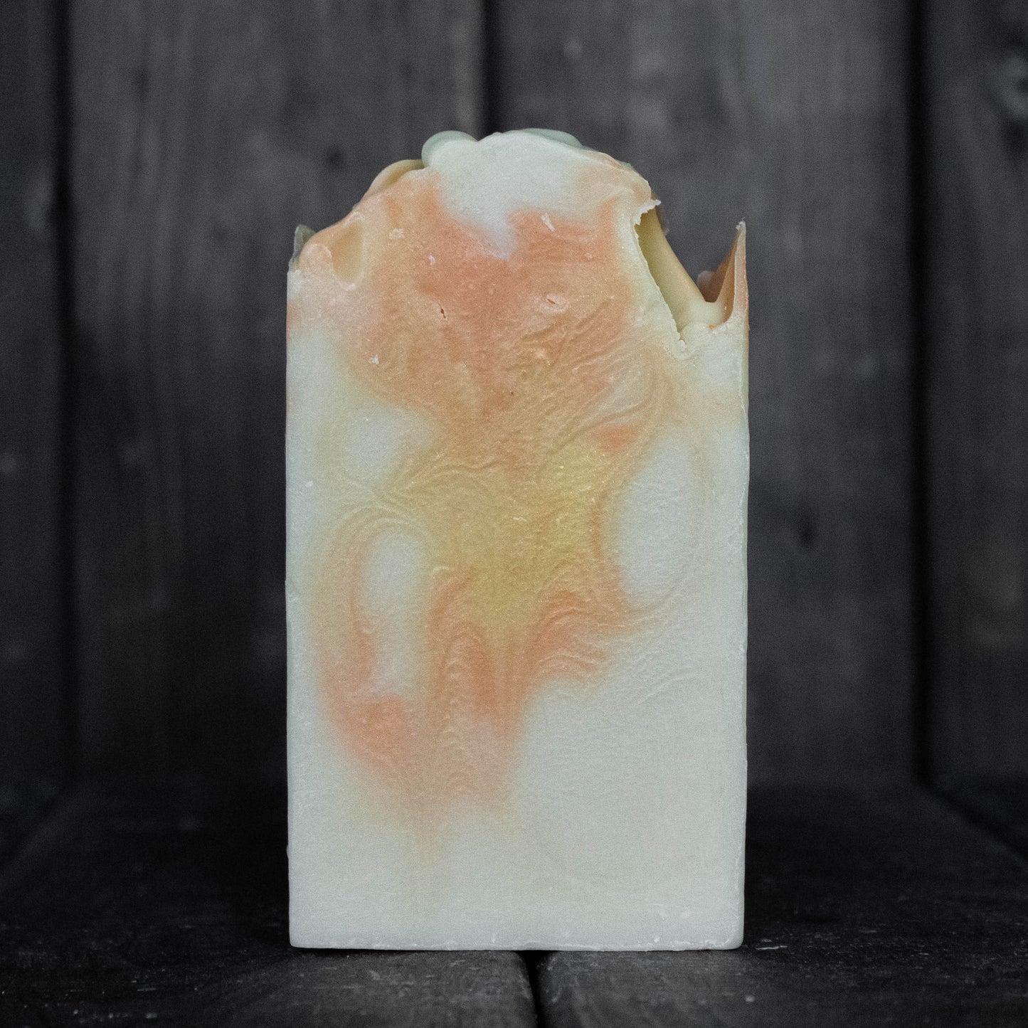 Soap with orange and yellow swirls in front of a dark wood background.