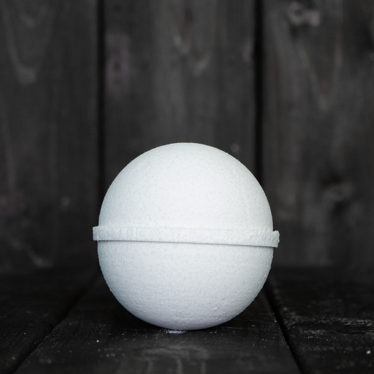 A white bath bomb in front of a dark wood background.