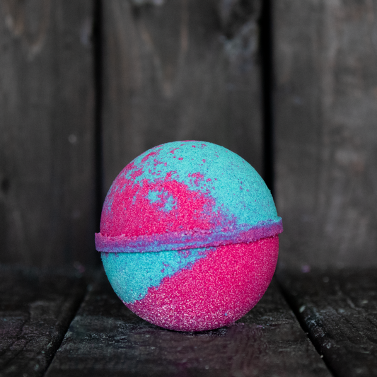 A red and green bath bomb in front of a dark wood background.