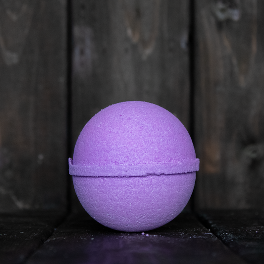 A purple bath bomb in front of a dark wood background.