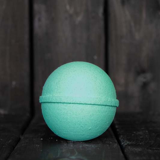 A turquoise bath bomb in front of a dark wood background.