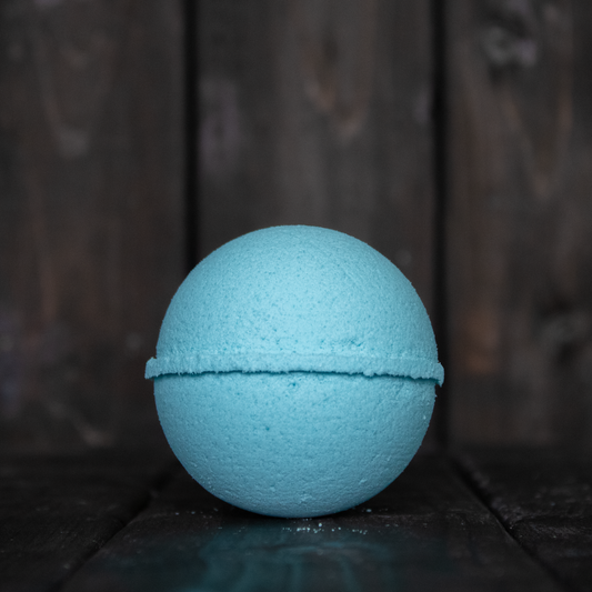 A blue bath bomb in front of a dark wood background.