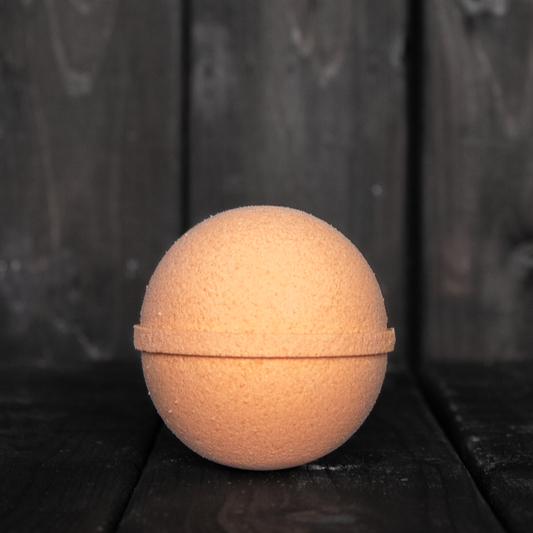 An orange bath bomb in front of a dark wood background.