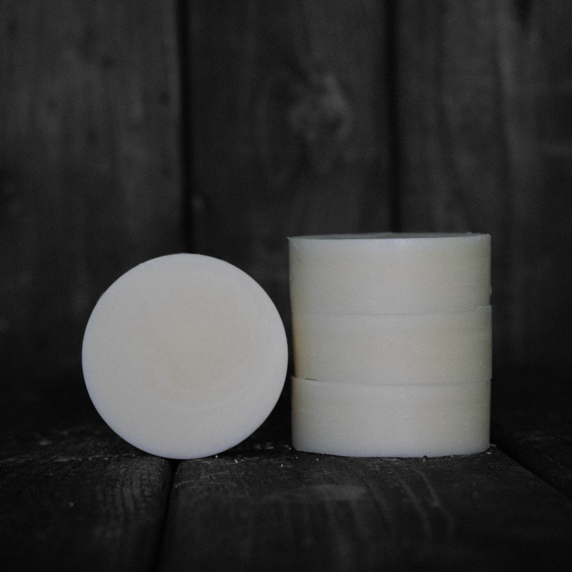A round cream coloured conditioner bar next to a stack of three cream coloured conditioner bars.