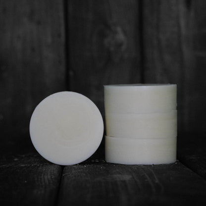 A round cream coloured conditioner bar next to a stack of three cream coloured conditioner bars.