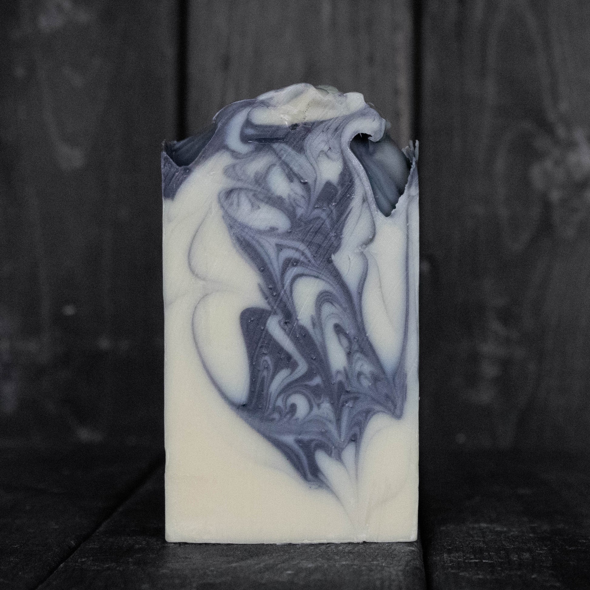 Soap with black swirls in front of a dark wood background.