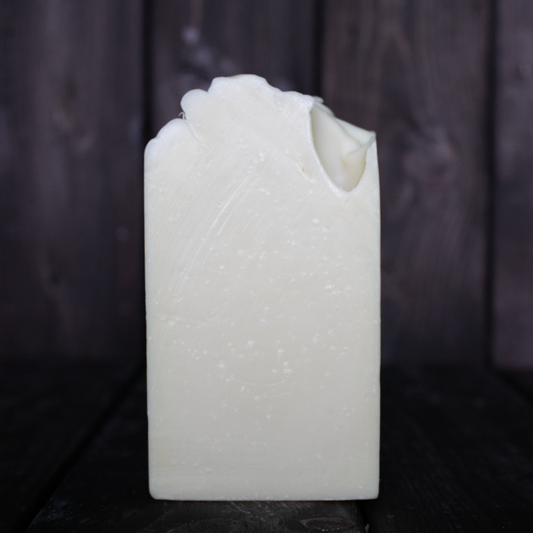 Beige soap in front of a dark wood background.