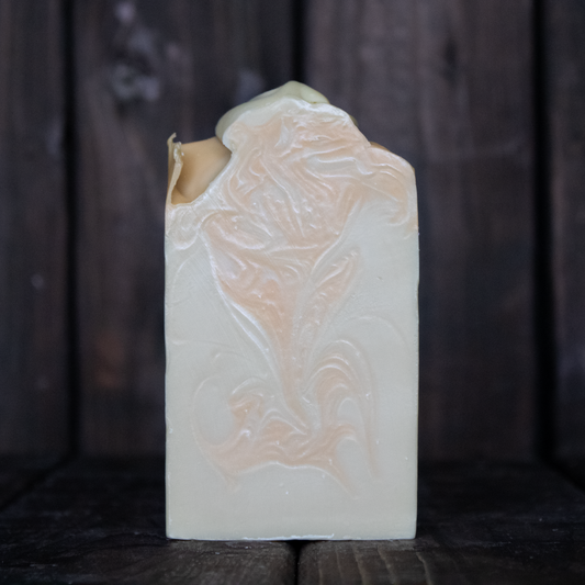 Soap with light brown swirls in front of a dark wood background.