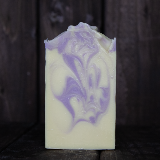 Soap with purple swirls in front of a dark wood background.