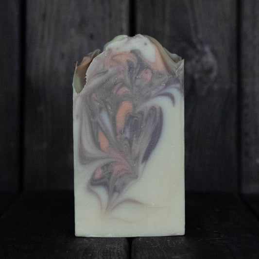 Soap with brown and orange swirls in front of a dark wood background.
