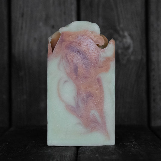 Soap with orange and red swirls in front of a dark wood background.