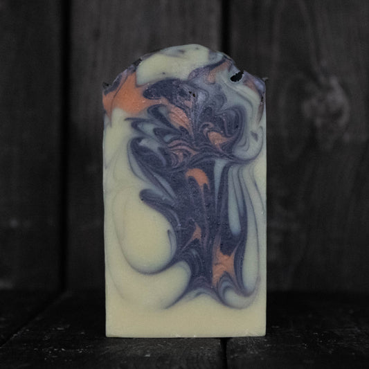Soap with black and orange swirls in front of a dark wood background.