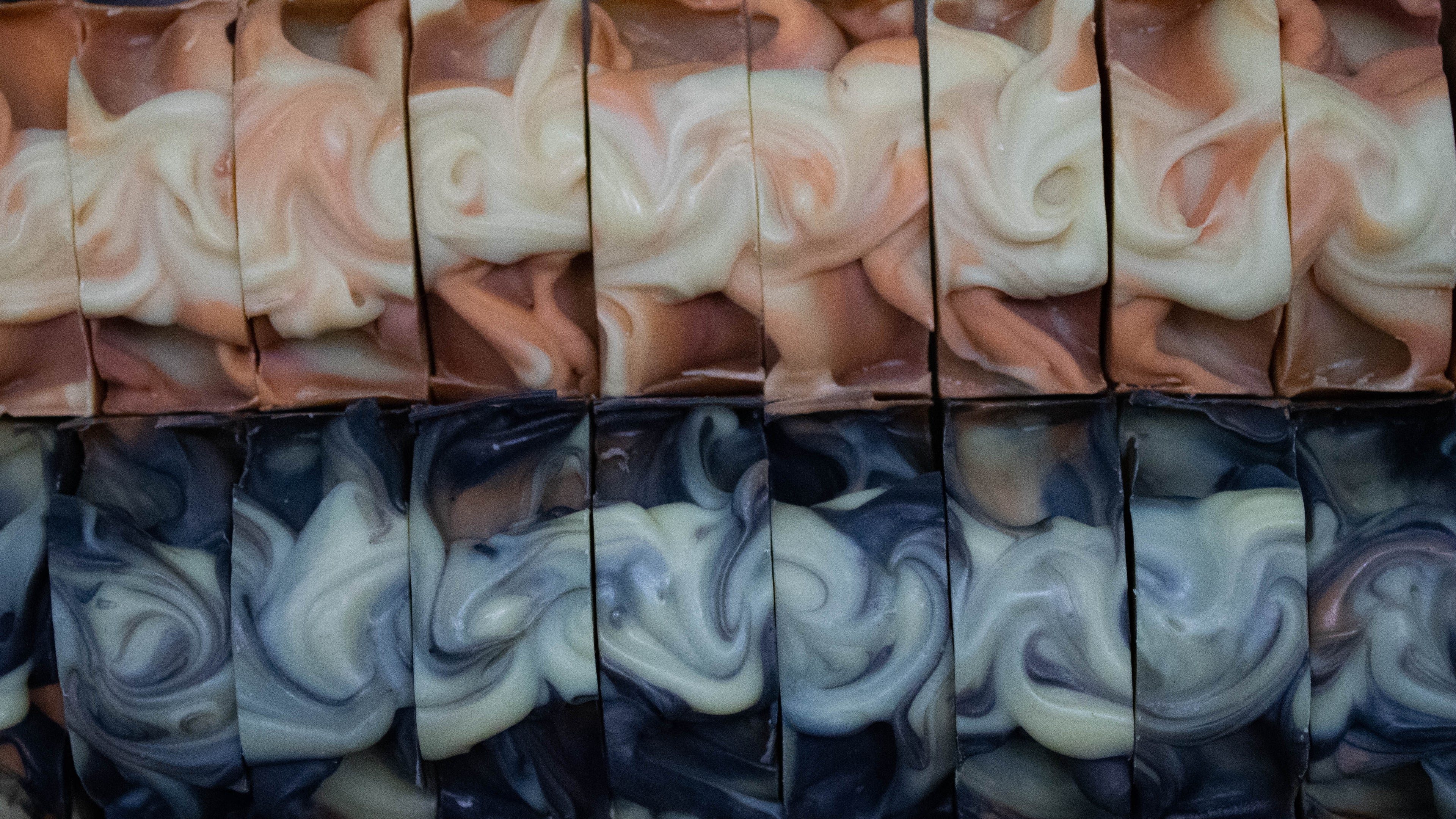 Orange, red, and cream coloured textured soap tops above black, orange, and cream coloured textured soap tops.